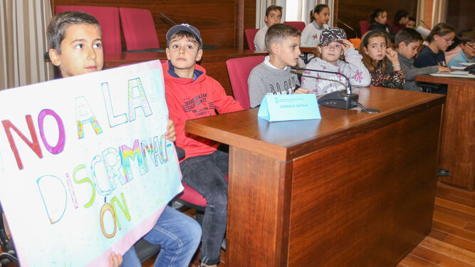 Un joven estudiante muestra su rechazo a la discriminación con una pancarta en el Salón de Plenos.