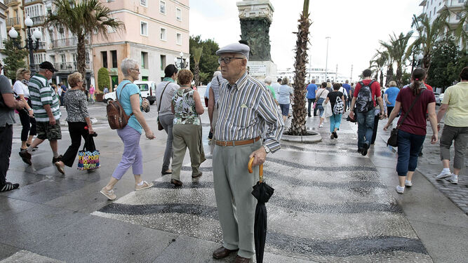 Un señor cede el paso a un grupo de turistas que atraviesa la Plaza de San Juan de Dios.