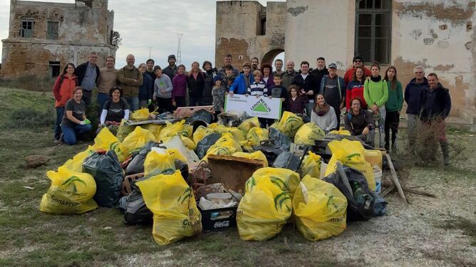 Algunos de los voluntarios participantes en la limpieza, junto a parte de la basura eliminada de la Isla