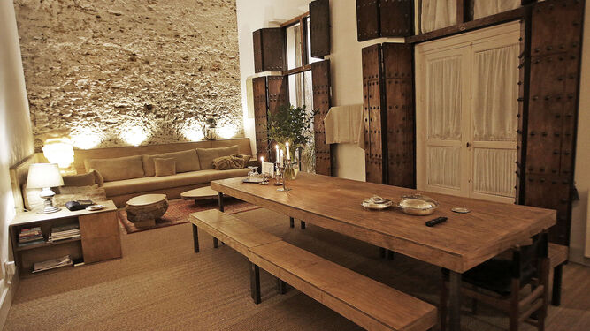 Imagen del salón con la amplia mesa de comedor y el sofá al fondo.