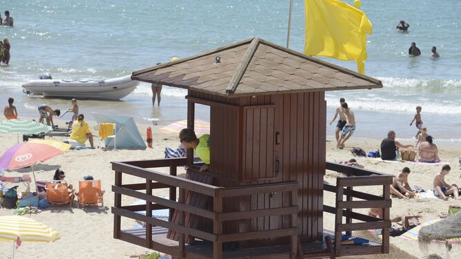 Un vigilante supervisa a los bañistas en una playa de la capital gaditana en verano.