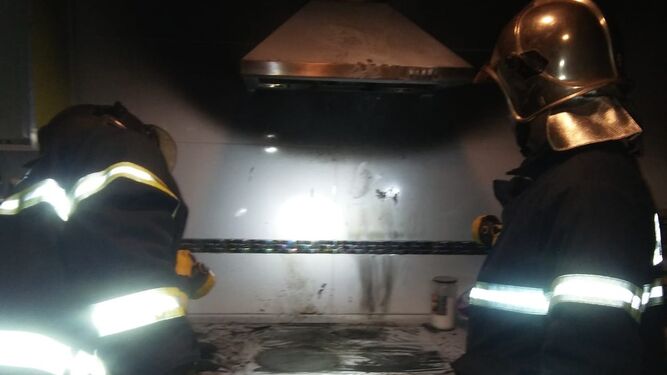 Dos bomberos comprueban el estado de la cocina, tras el incendio.