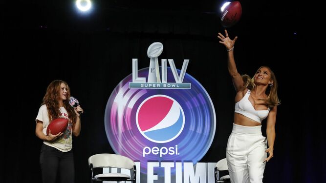 JLo lanza un balón de fútbol americano ante la presencia de Shakira, en la presentación de su 'show' en la 'Superbowl'.