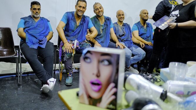 Germán Rendón, a la derecha, se maquilla sentado junto a integrantes de su comparsa.