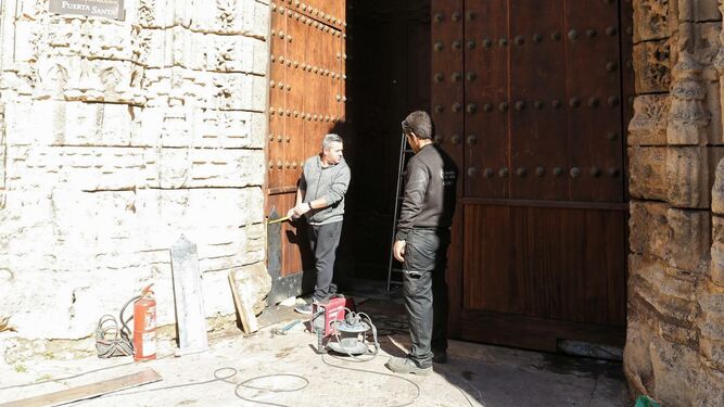 Imagen de dos de los restauradores que trabajan actualmente en la puerta del Perdón.
