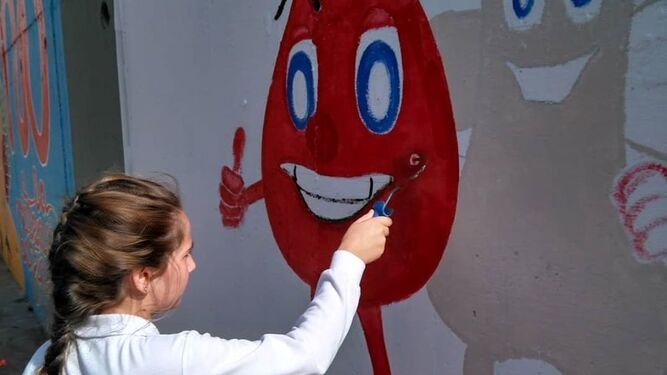 Una de las alumnas pinta el mural de Apo Leu a favor de la donación de sangre y médula.