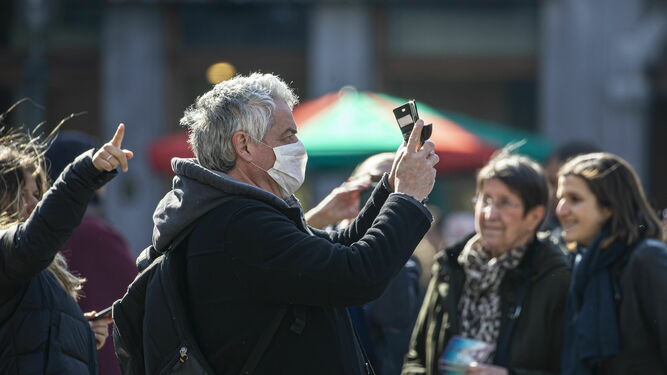 Un hombre con mascarilla se fotografía con el teléfono móvil.