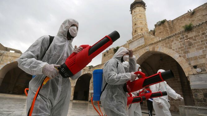 Dos trabajadores desinfectan territorio palestino