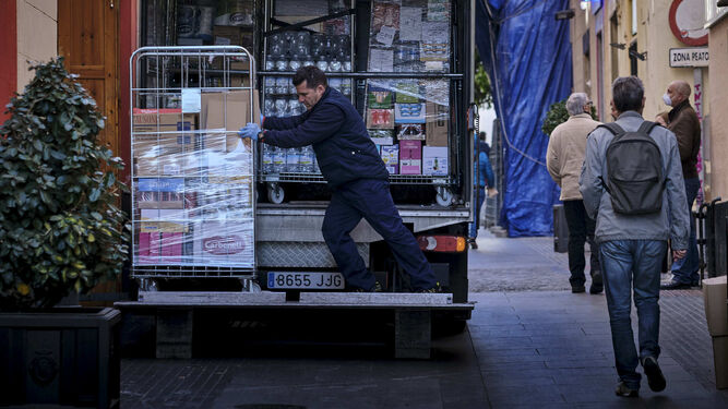 Un transportista abastece de art&iacute;culos para su venta a un supermercado en la calle San Francisco