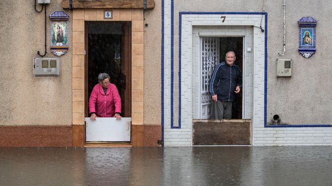 Vecinos de la zona de la plaza de toros intentan evitar que el agua se cuele en sus casas, durante las lluvias del pasado día 17.