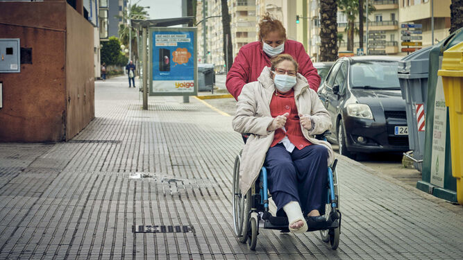 Una mujer en silla de ruedas y su acompa&ntilde;ante por la avenida