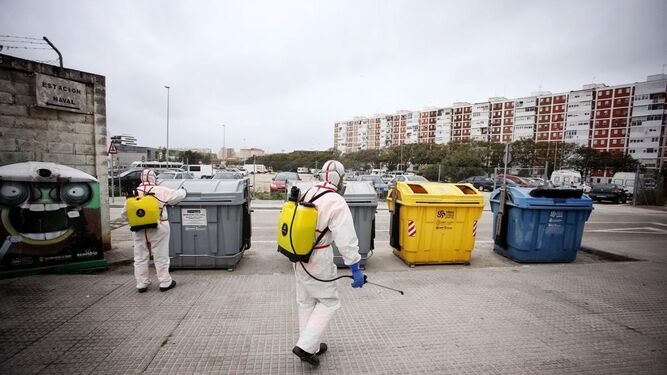 Operarios del servicio de limpieza desinfectan los contenedores del barrio.