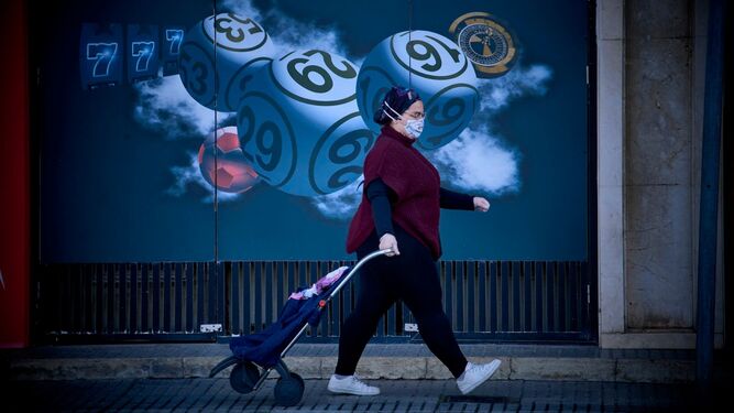 Un mujer camino de la compra con guantes y mascarilla.
