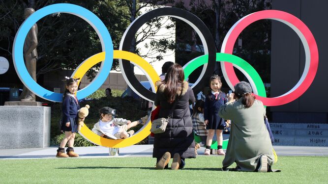 Unos niños se fotografían en Tokio junto a los aros olímpicos.