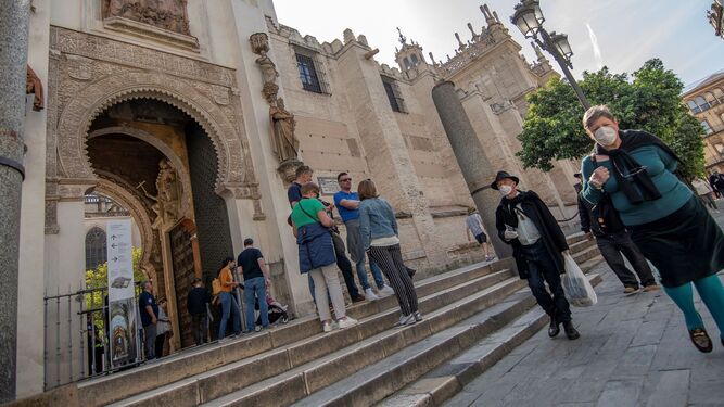 Turistas recorren con mascarilla, junto a la catedral de Sevilla.