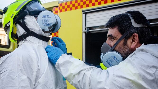 Bomberos ajustan sus equipos de protección durante las labores de desinfección.