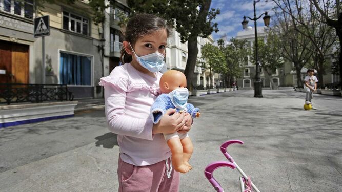 Una niña y su muñeca con mascarilla en un paseo por Cádiz esta mañana.
