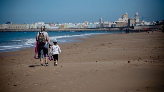 Una familia paseando por una playa de Cádiz.