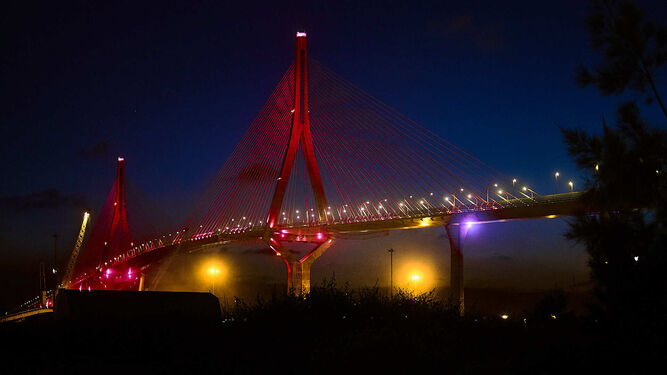 El puente de la Constitución 1812 de Cádiz iluminado de rojo, con motivo del Día de la Cruz Roja