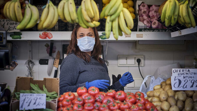 Una de las detallistas del Mercado Central, en su puesto, protegida con guantes y mascarilla.