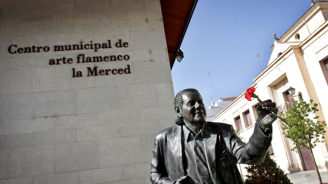 El monumento al cantaor Chano Lobato, frente a la fachada del Centro Municipal de Arte Flamenco  la Merced, con un clavel que fue colocado por un vecino