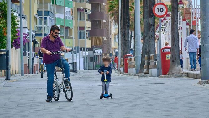 Un padre circula en bicicleta junto a su hijo, que va en patinete, por el Paseo Marítimo.