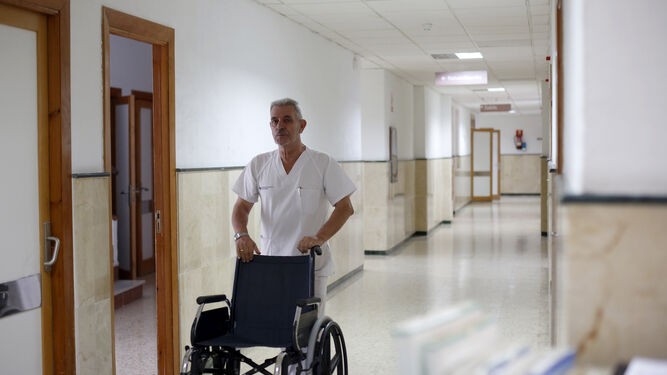 Un empleado del Hospital San Rafael empuja una silla de ruedas.