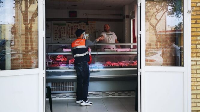 Voluntarios de Protección Civil entregan mascarillas en una carnicería.