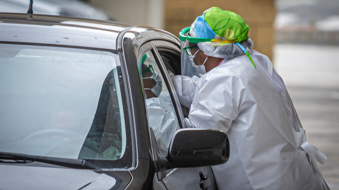 Una sanitaria realiza una prueba de coronavirus a una persona que está dentro de un vehículo.