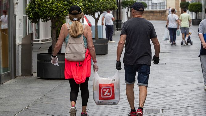 Dos personas caminan por la calle Rosario portando una bolsa de la compra.