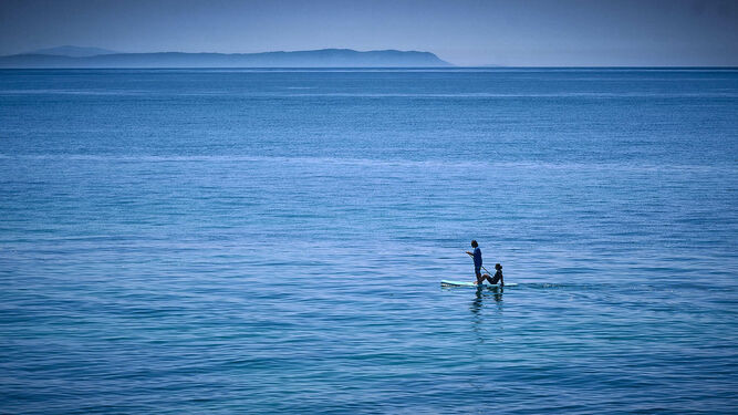 Playas de Barbate. Una pareja navega en una tabla de Paddle Surf frente a la costa de Barbate. Al fondo el cabo Espartel, ya en continente africano.