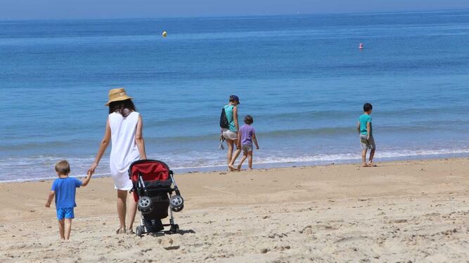 Varias personas caminan por la playa de La Barrosa.