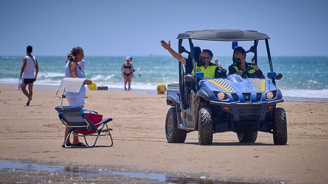 Agentes de la Policía Local advierten de las medidas de seguridad a una usuaria de la playa.
