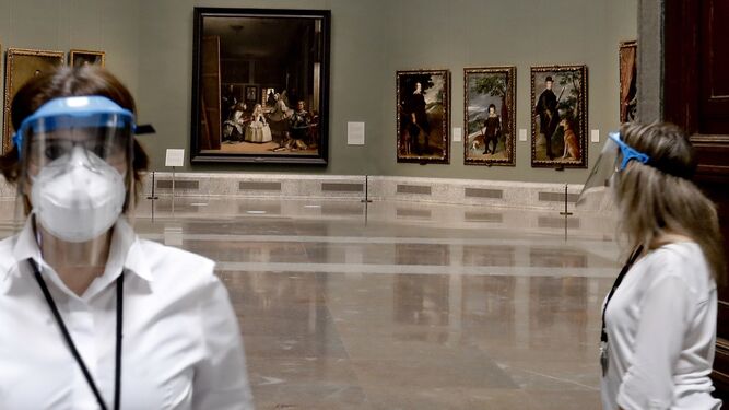 Dos trabajadoras del Prado, con mascarillas, con 'Las Meninas' al fondo.