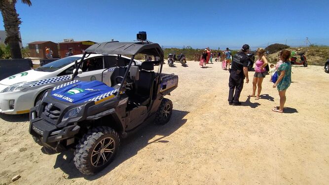 Un agente de la Policía Local informa a los bañistas en el único acceso disponible de la playa de Camposoto.
