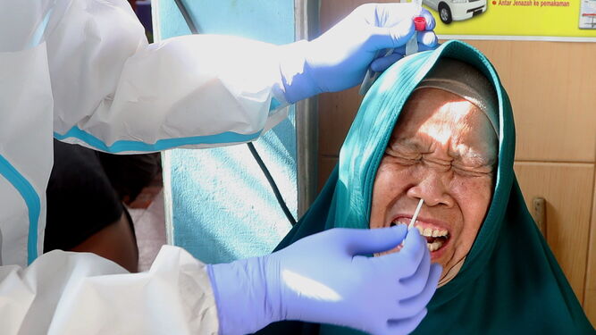 Un técnico sanitario le practica el test del coronavirus a una anciana en la ciudad indonesia de Jakarta.