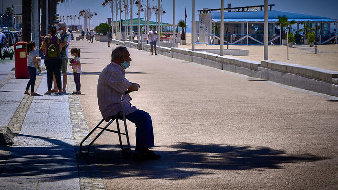 Un hombre busca la sombra para protegerse del calor en el paseo marítimo de Cádiz.