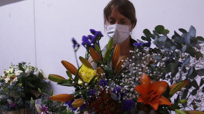 Una mujer con flores y una mascarilla.