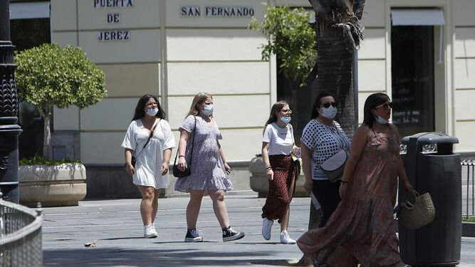 Varias personas pasean por Sevilla con mascarillas puestas