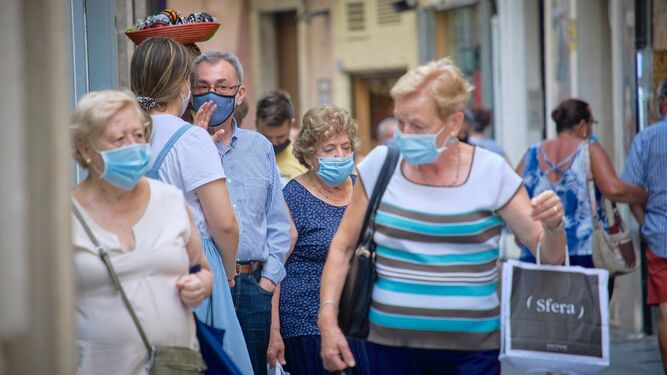 Personas mayores pasean por las calles de Cádiz con sus mascarillas.