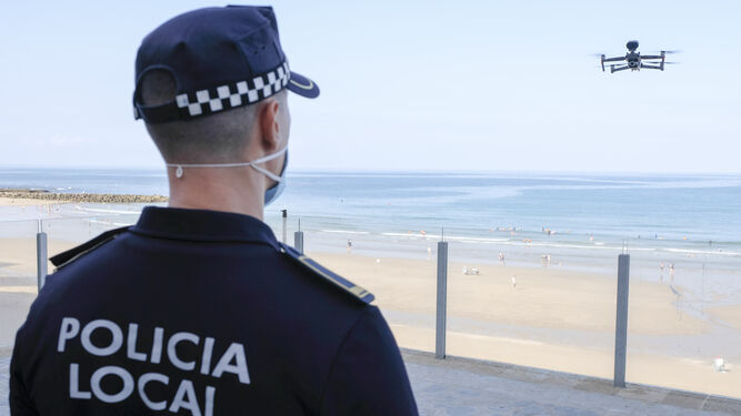 Un policía local vigila el vuelo de un dron en Santa María del Mar.