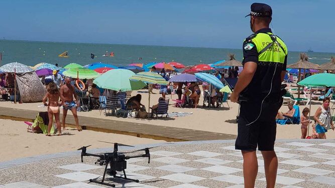 Un agente de la Policía Local de Chipiona pilota uno de los drones para controlar el aforo.