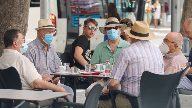 Un grupo de jubilados en un bar con mascarillas durante la pandemia