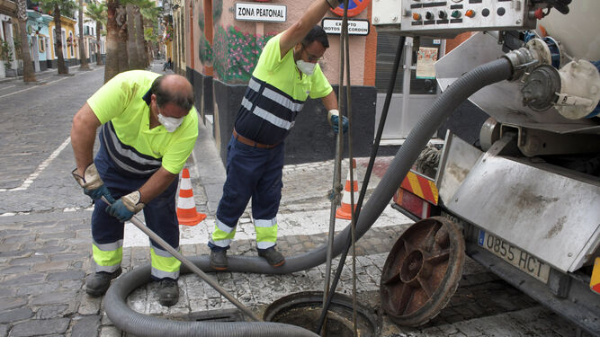 Empleados de Aguas de Cádiz trabajan en la limpieza de la red de saneamiento en la esquina en la calle Virgen de la Palma.