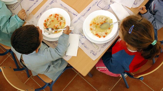Alumnos almuerzan en un comedor escolar.