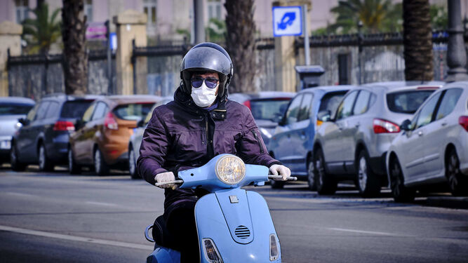 Una persona con mascarilla y guantes en una moto.