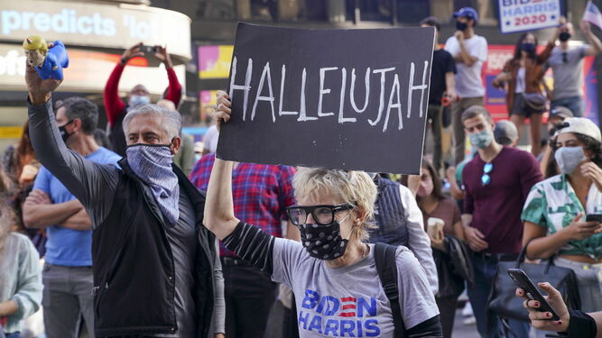 Una mujer levanta una pancarta en las calles de Nueva York durante una de las celebraciones espontáneas que se registraron ayer tras conocerse la victoria de Joe Biden.