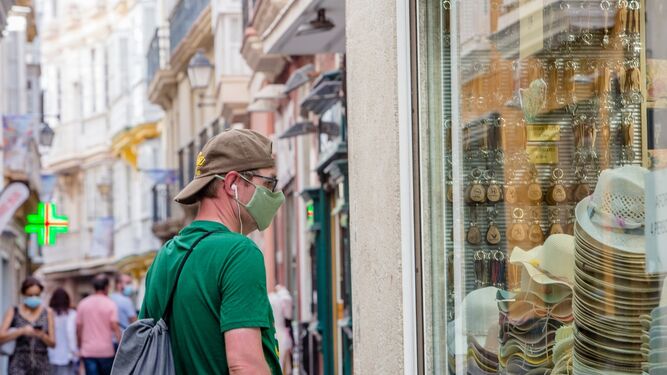 Un joven, frente al escaparate de un comercio del centro de Cádiz