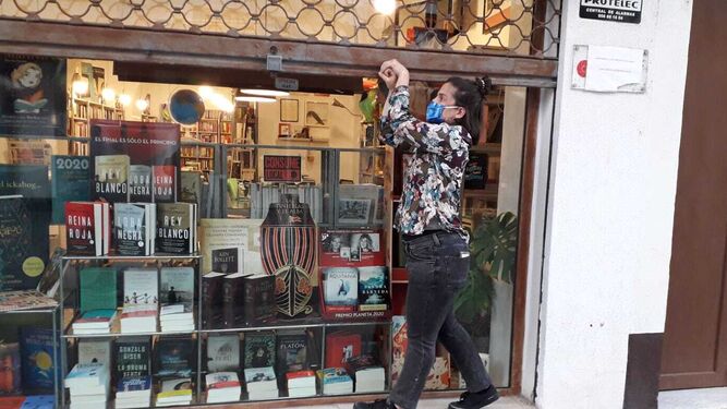 La propietaria de la Librería Zorba, echando la persiana  a las seis de la tarde.
