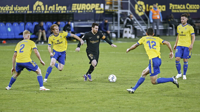 Cuatro jugadores del Cádiz rodean a Messi, que conduce el balón.